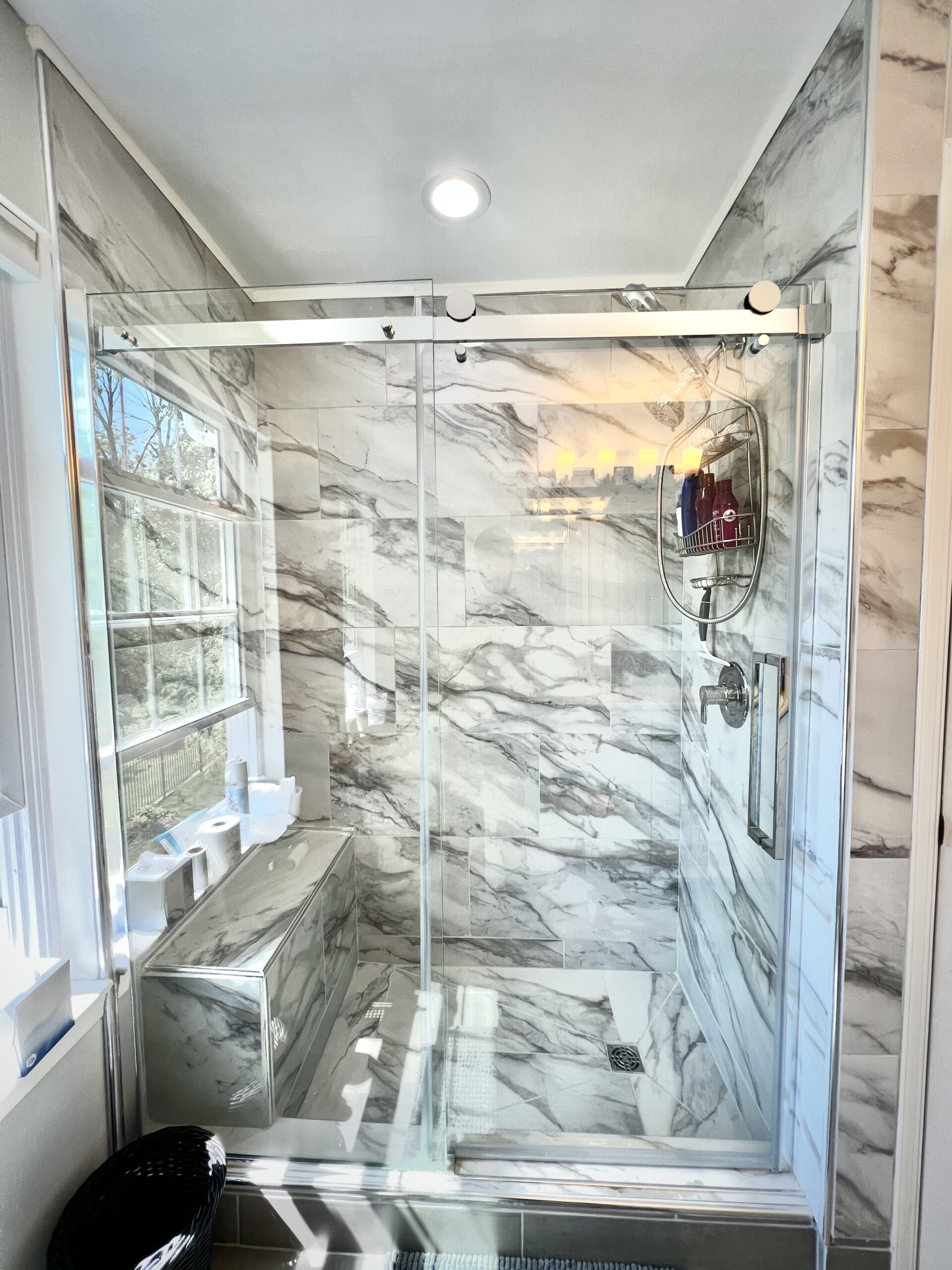 Marble-look walk-in shower with built-in bench and frameless glass enclosure