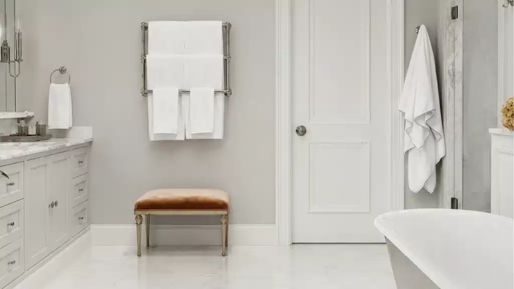 Luxurious master bathroom remodel with white cabinetry, marble countertops, freestanding soaking tub, and heated towel rack