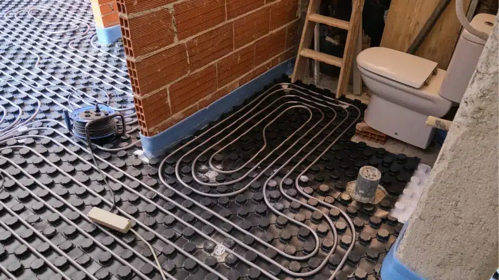 Radiant floor heating system installation with tubing layout in bathroom renovation project