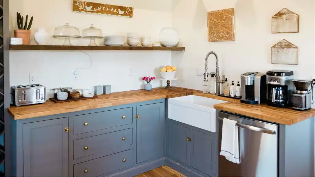 Farmhouse kitchen with blue-gray inset cabinets, butcher block counters, and white apron-front sink