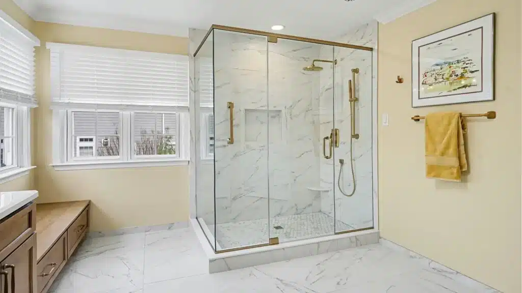 Marble-look walk-in shower with frameless glass and brushed gold hardware