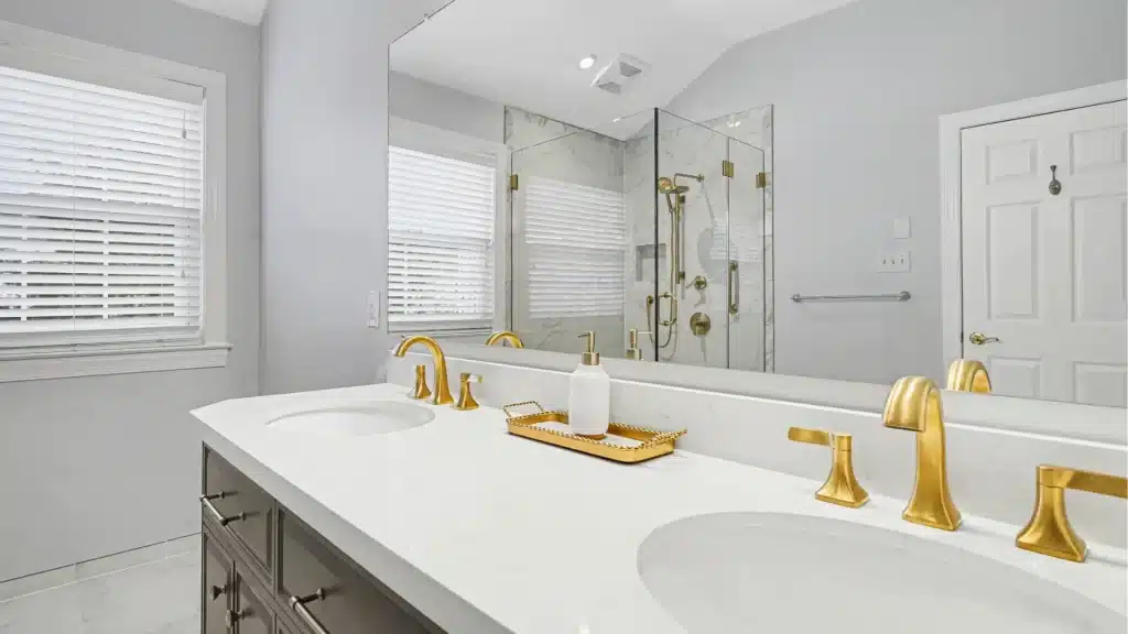 Gray double vanity with quartz countertop and brushed gold bathroom faucets
