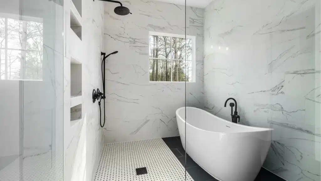 Freestanding soaking tub beside a marble-look walk-in shower