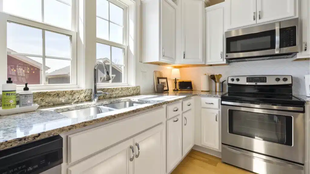 Modern kitchen remodel with white shaker cabinets, granite countertops, stainless steel appliances, and large windows