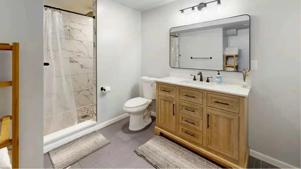 Bathroom vanity with wood cabinetry, quartz counter, and tub shower surround