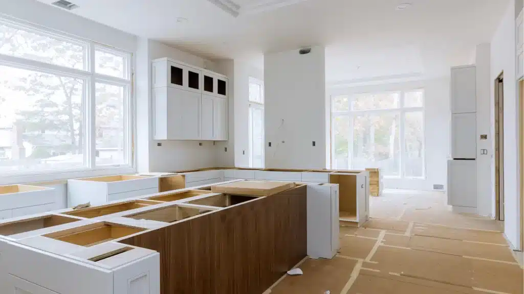 Modern kitchen remodel in progress with white cabinetry, wood island, and new construction framing