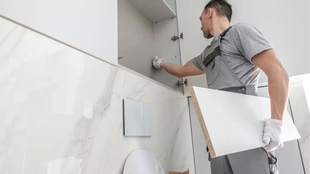 Installer mounting large marble-look wall tile in a bathroom remodel
