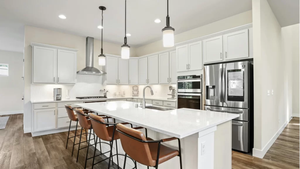 Modern kitchen remodel with white shaker cabinets, quartz island countertop, stainless steel appliances, and pendant lighting