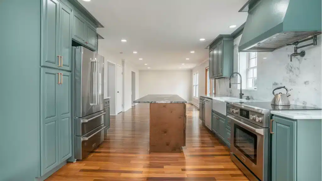 Modern kitchen remodel with sage green cabinets, granite island, stainless steel appliances, and hardwood floors