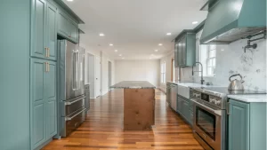 Modern kitchen remodel with sage green cabinets, stainless steel appliances, marble backsplash, and hardwood flooring