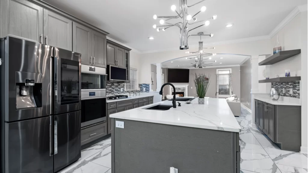 Modern kitchen remodel with gray cabinetry, marble countertops, stainless steel appliances, and island by Pottstown Construction