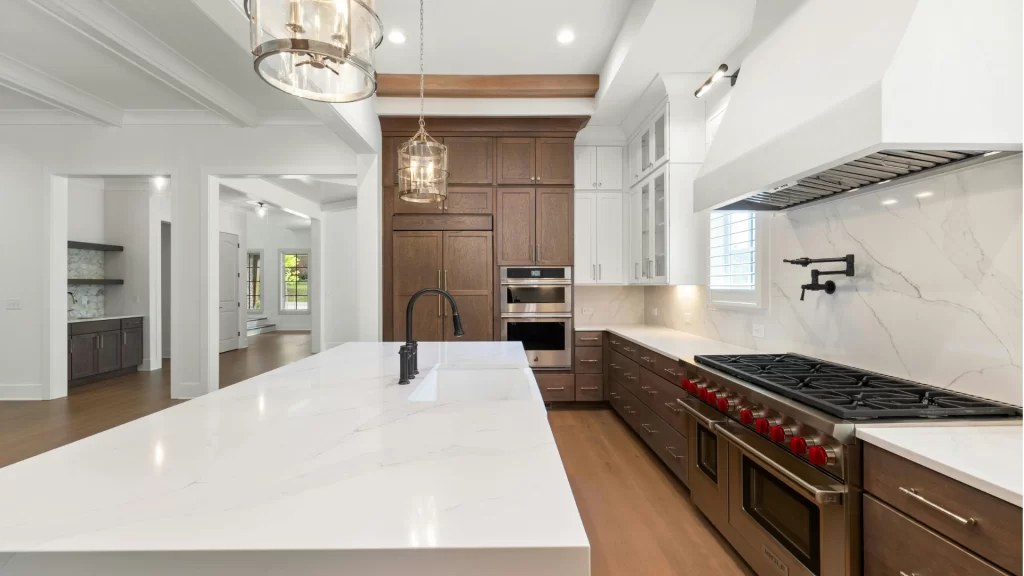 Modern kitchen remodel with white shaker cabinets, quartz countertops, and dark wood island with professional gas range