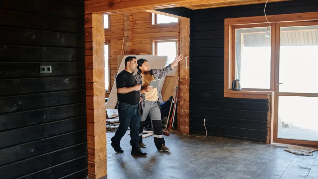 Contractors reviewing home renovation plans in open garage space with wooden beams and glass doors