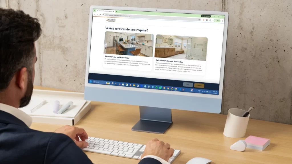 Man viewing Pottstown Construction Company website showing kitchen and bathroom remodeling services on desktop monitor