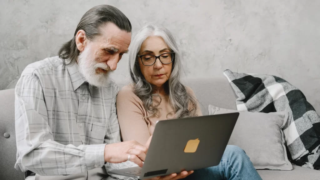 Older couple reviewing home renovation project on laptop together on couch