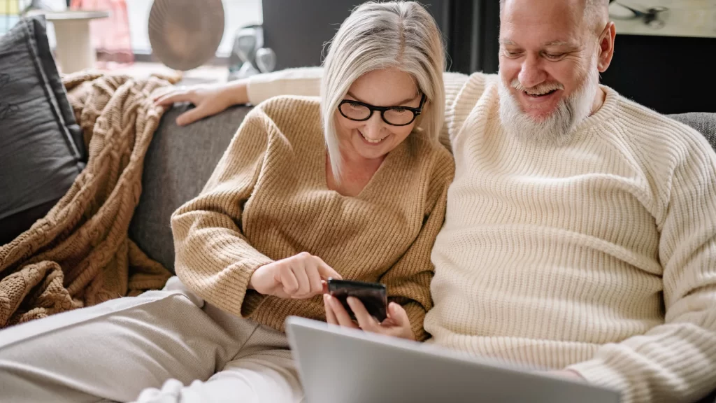 Couple reviewing home renovation plans on laptop and tablet in modern living room