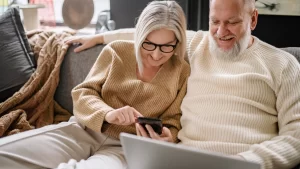 Couple reviewing home renovation plans on laptop and tablet in modern living room